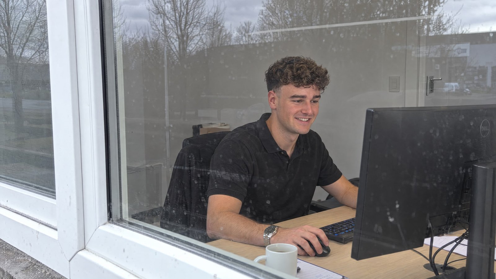 Jesse achter zijn computer, gezien door het raam