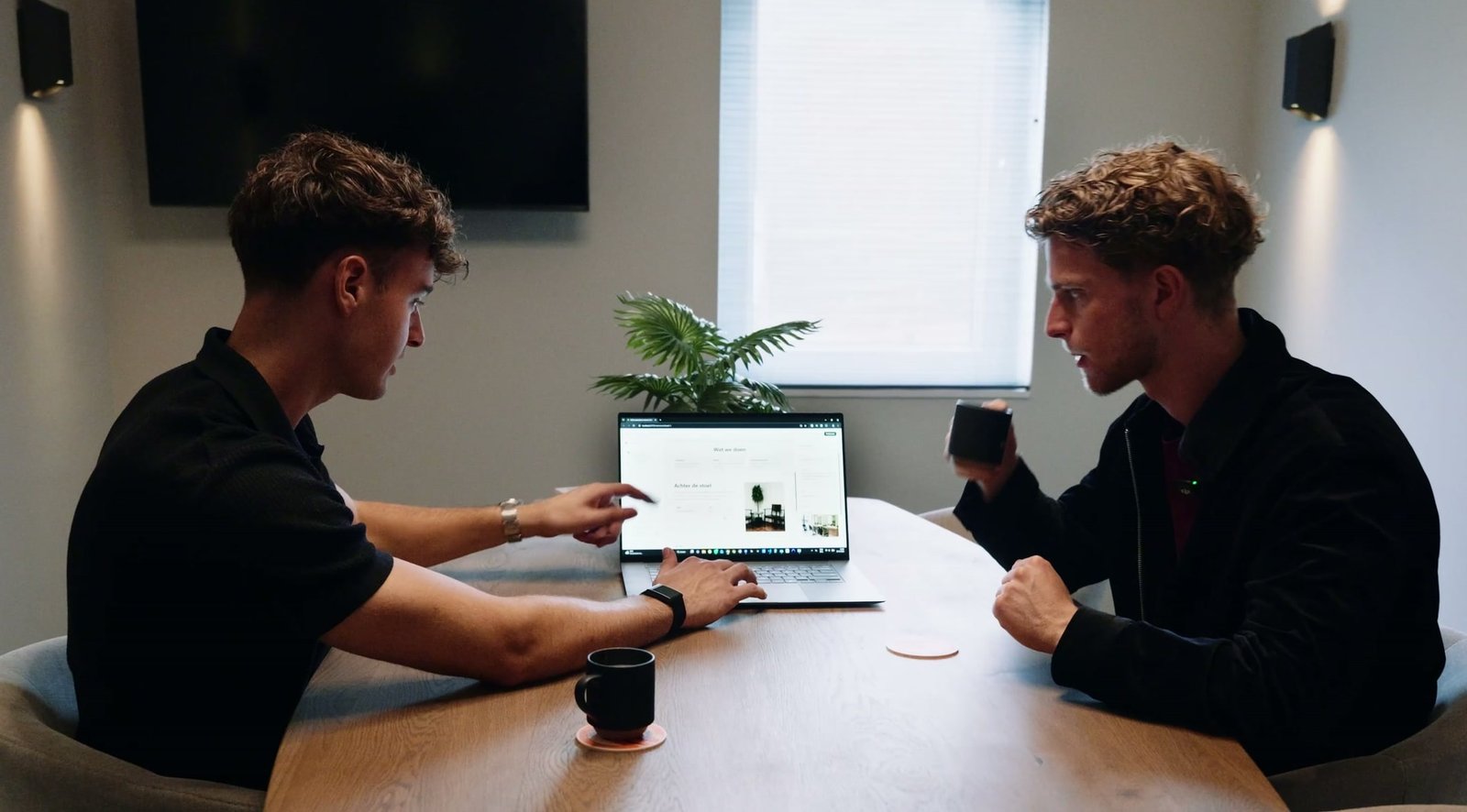 Twee mensen aan tafel achter een laptop