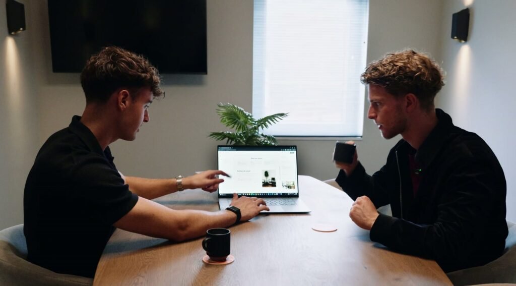 Twee mensen aan tafel achter een laptop